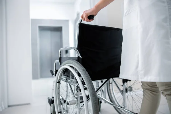 Женщина-врач с пустой инвалидной коляской в холле — стоковое фото