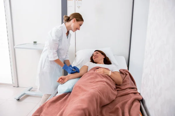 Mosolygó női orvos tartja Cseppentő a beteg — Stock Fotó