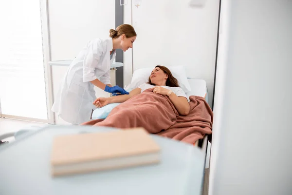 Leende sjukvårdare tittar på kvinnlig patient — Stockfoto