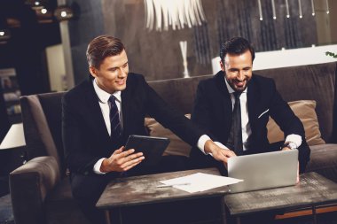 Genç adam gülümseyerek ve meslektaşının dizüstü işaret