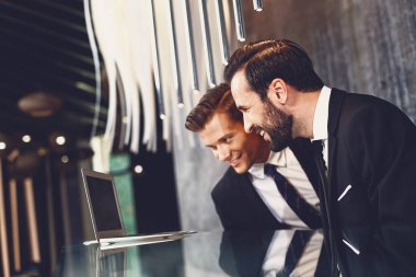 Neşeli arkadaşlar gülümseyerek ve modern cihazın ekranına bakıyor