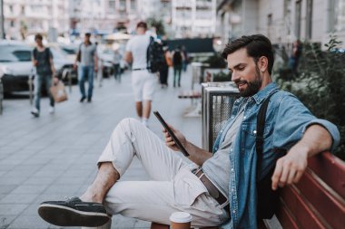 Neşeli erkek dışarıda elektronik tablete bakıyor.