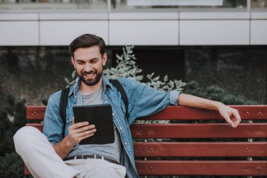 Dışarıdaki dijital cihazları izleyen olumlu adam.