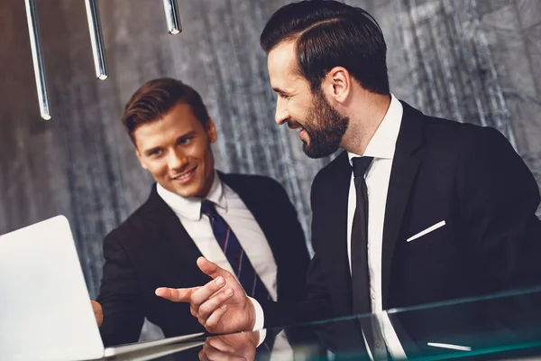 Hombres elegantes confiados sonriendo y señalando a la pantalla de la computadora portátil moderna —  Fotos de Stock