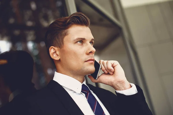 Närbild av allvarlig ung man i svart kostym pratar i telefon — Stockfoto