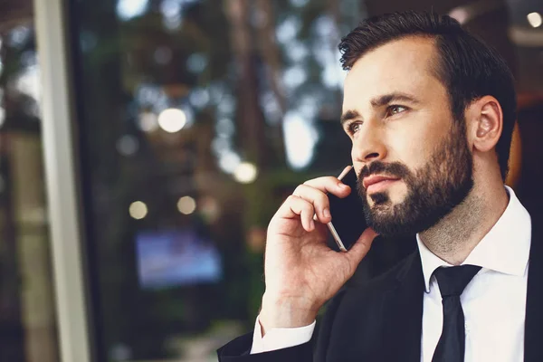 Primer plano del joven barbudo buscando calma mientras habla por teléfono — Foto de Stock