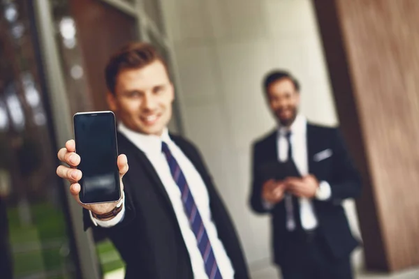 Homem elegante mostrando a tela de seu smartphone ao ar livre — Fotografia de Stock