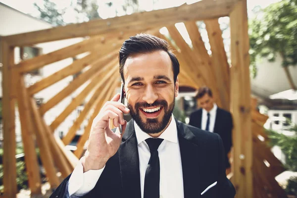 Крупным планом бородатый молодой человек улыбается и приятно разговаривает по телефону — стоковое фото