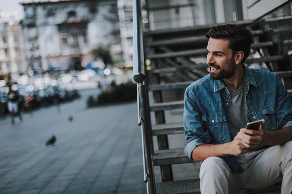 Hombre sonriente usando el teléfono moderno al aire libre — Foto de Stock