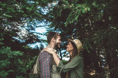 Gülümseyen sevgili çift yeşil ormanda seyahat ediyor.