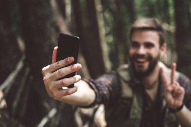 Neşeli gezgin ormanda selfie çekiyor.