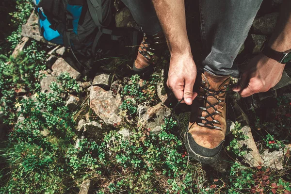 Traveler man fasten shoe-laces on green hill — ストック写真