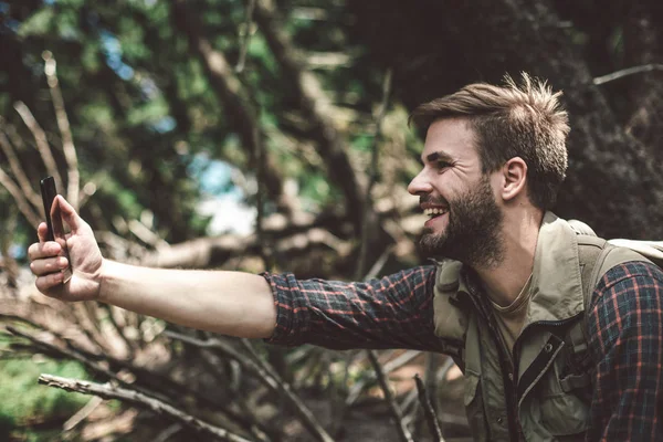 Веселый путешественник делает селфи в лесу — стоковое фото