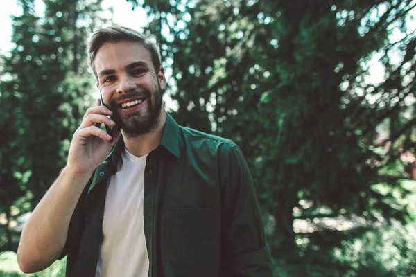 Utazó férfi beszél telefonon zöld erdőben — Stock Fotó