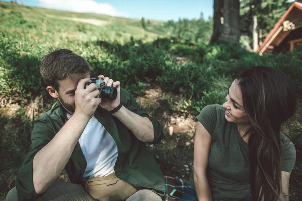 Hombre joven tomando fotos de la mujer en la colina verde — Foto de Stock