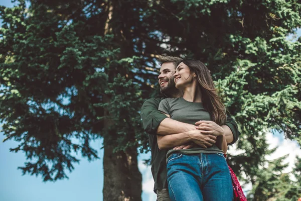 Älskade par står i omfamning nära grönt träd — Stockfoto