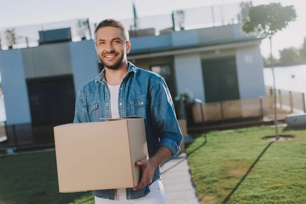 Cintura para arriba de un hombre agradable sosteniendo una caja de papel — Foto de Stock