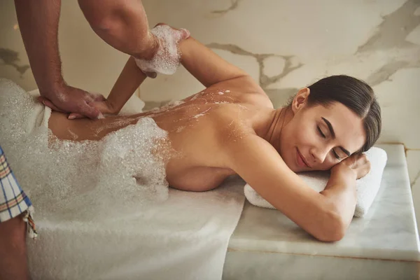 Friedliche Dame lächelt und genießt Seifenschaum-Massage — Stockfoto