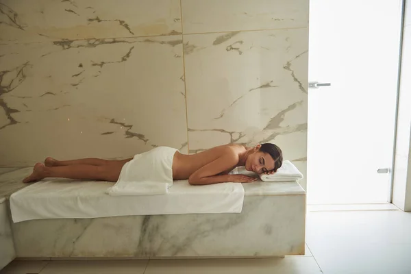 Лаконичное фото юной леди, лежащей на полотенце в турецкой бане — стоковое фото