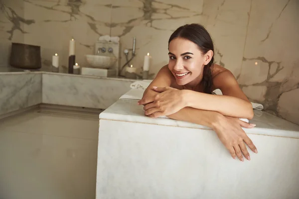 Vreugdevolle jonge dame glimlachend en kijkend naar je terwijl je in Turks bad — Stockfoto