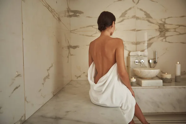 Beautiful back of young lady sitting in Turkish bath