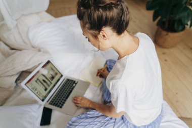 Genç bayan yatak odasında çalışıyor.