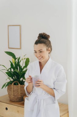 Gülümseyen genç bayan yatak odasında duruyor.