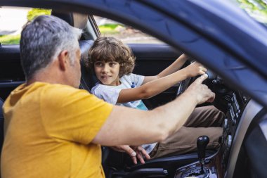 Beyaz yetişkin bir adam arabadaki bir şeyi işaret ediyor.