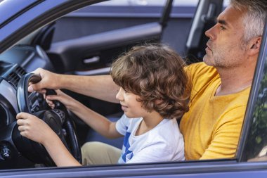 Ciddi bir adam oğluna direksiyon dersi veriyor.
