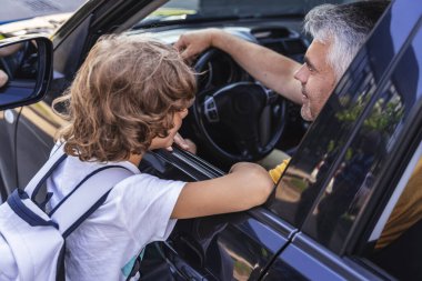 Kafkasyalı bir adam okul çocuğunu okula uğurluyor.