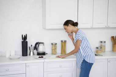 Telefonda konuşan ve notları okuyan meşgul bir kadın.