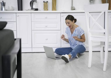 Akıllı telefonu ve dizüstü bilgisayarda fotoğrafı olan heyecanlı bir kadın.