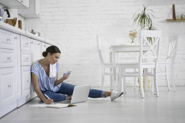 Ev fotoğrafı çekilirken not almakla meşgul bir kadın.