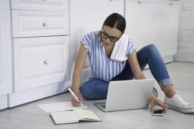 Yazmakla ve akıllı telefonlardan fotoğraf çekmekle meşgul bir kadın.