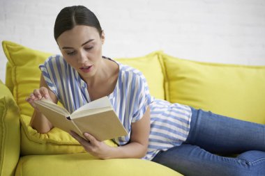 Evdeki resimde yeni kitap okuyan meraklı kadın.