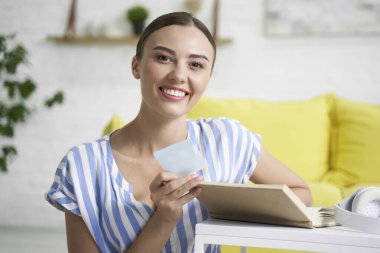 Elinde kitap ve not defteri olan gülümseyen kadın.