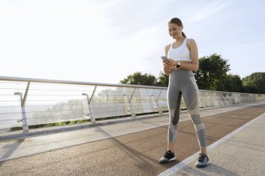 Antrenmanda cep telefonu olan mutlu atletik bayan.