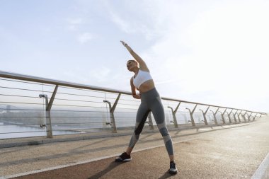 Neşeli atletik bayan yan vücut büküyor.