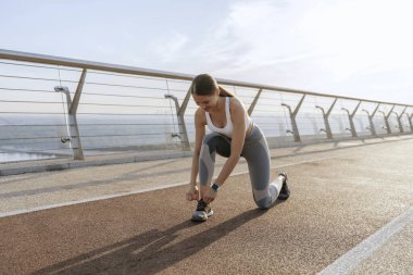 Spor ayakkabılarının bağcıklarını bağlayan mutlu atletik kadın