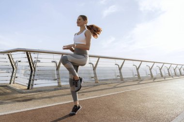 Genç bayan yaya köprüsünde koşuyor.