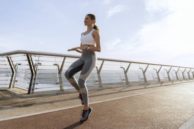 Genç bayan köprüde koşuyor.