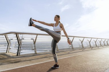 Sportif bayan yaya köprüsünde bacak sallıyor.