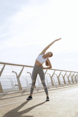 Gülümseyen atletik kadın yan vücut büküyor.