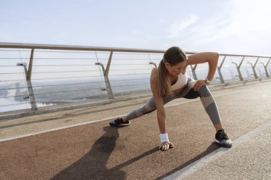 İnce atletik bayan yan bacakları esnetiyor.