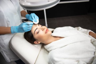 Cosmetologist with sponge is using blackhead remover