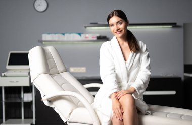 Kozmetik kürsüsünde oturan neşeli genç kadın.