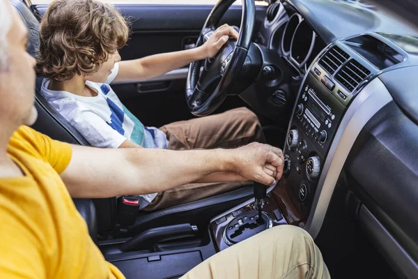 Homme caucasien enseigne petit garçon comment conduire une voiture — Photo