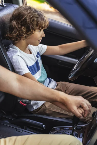 Белый мужчина помогает маленькому мальчику водить машину — стоковое фото