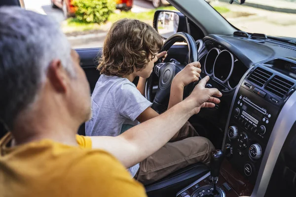 Beyaz bir adam arabanın içinde küçük bir çocukla konuşuyor.
