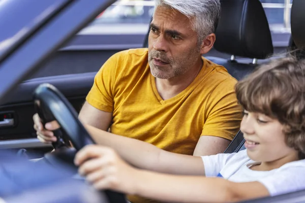 Padre guapo enseñando a su hijo a conducir un vehículo — Foto de Stock